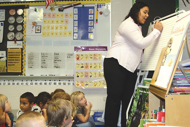 Cassie Scoggins writes the daily message with the help of kindergartners at Bush Elementary School. Scoggins helps teach the students as a "cadet teacher."