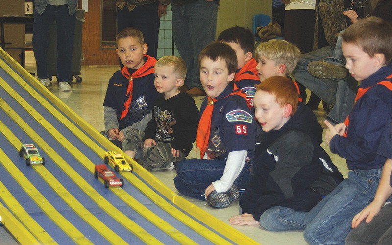 Cub Scouts of Pack 55 watch as some of their cars race down the track during the pack's Pinewood Derby Tuesday night at McIntire Elementary School. Members of the Fulton Breakfast Optimist Club judged the race.
