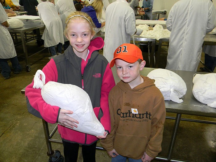Molly Dampf, left, with brother Isaac, both Shamrock 4-H Club members, after preparing hams to cure at Burgers' Smokehouse Saturday, Jan. 7.
