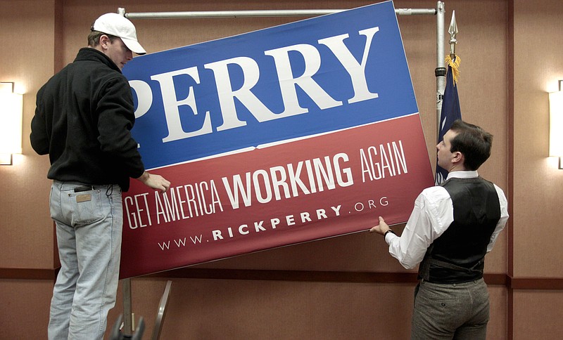 Campaign workers Ryan Vise, left, and Lucas Baiano remove a sign following a Thursday news conference in North Charleston, S.C., where Republican presidential candidate Texas Gov. Rick Perry announced he is suspending his campaign and endorsing Newt Gingrich. 