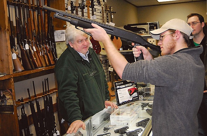 Tyler Williams checks out a shotgun at Capital Pawn last week as store owner Bob McEowen looks on. 