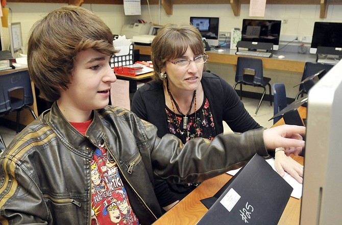 Aidan Gallagher explains to teacher Karen Distler what he's recently learned about creating a movie on the computer. He is one of several students participating in the new Tech Club at Lewis & Clark Middle School.