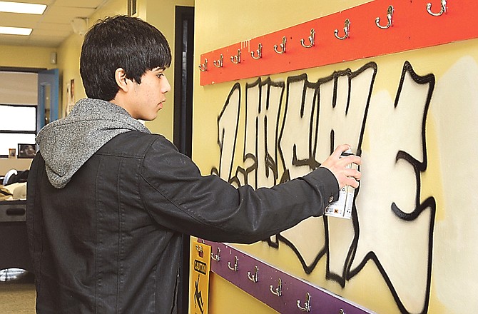 Alex Bravo paints the word "LISTEN" on an interior wall at the Boys and Girls Club. Each Monday for the next several weeks, he will paint a Character Plus word on a different wall.