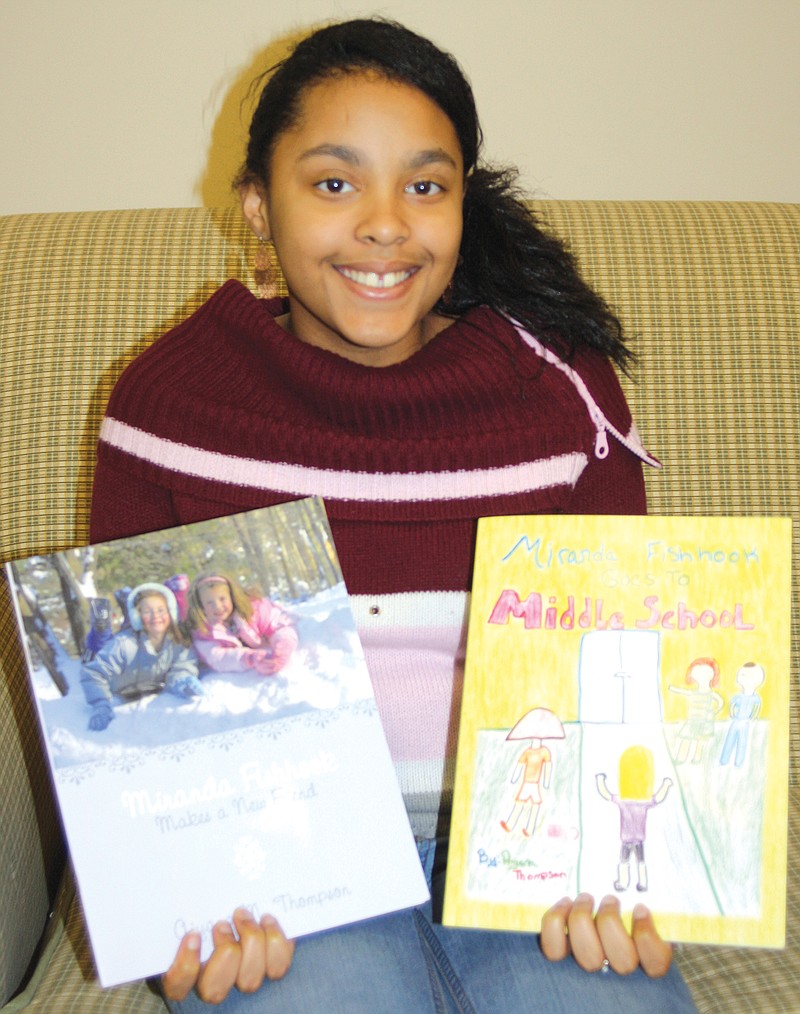 Aiyana Thompson holds the two books she authored and illustrated.