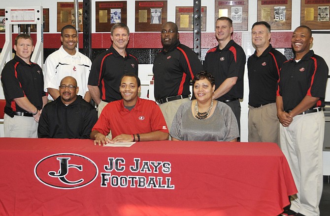 Devon Moore of Jefferson City High School (seated center) signs a letter of intent to play football at Western Illinois University in Macomb, Ill. Also seated are his parents Raymond Bradford Jr. and Johnetta Moore. (Standing, left to right) Jays assistant football coach Jeff West, Jays assistant basketball coach Ray Hughes, Jays head football coach Ted LePage, Jays assistant football coach Michael Washington, Jays football assistant coach Dan Ridgeway, Jays head basketball coach Blair Thompson and Jays assistant football coach Lerone Briggs.