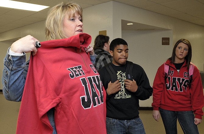 Regina Roe holds up a pullover sweatshirt to see if it is her size as students sell them in the hallway before the start of class. Next to her are seniors Lorenzo Greene and Hannah Dahl, both students in the Entrepreneurship Class at Nichols Career Center.