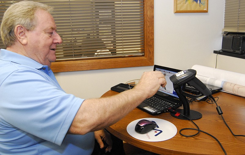 Cole County Clerk Marvin Register demonstrates the new ID scan system. The system also features a signature pad so the voter verification process will be paperless.