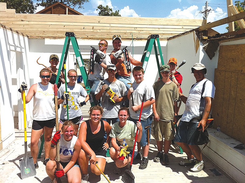 Young adults with the Crossroads Youth Group of Central Christian Church in Fulton help put a roof on a house in Joplin last summer. The group has completed raising funds for an African well.