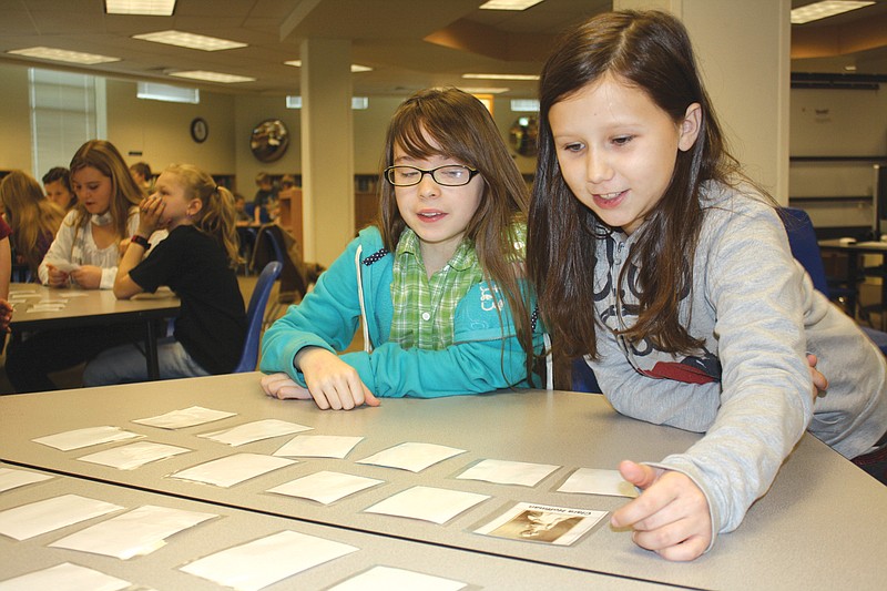 Fourth-graders (left) Mackenzie Martin, 10, and Shelby Wood, 10, play a memory game with photos of famous Missouri-born people Monday at Bush Elementary School. Bush's three fourth-grade classes listened to a presentation on Missouri workers and occupations in preparation for The Way We Worked exhibit's appearance at the National Churchill Museum.