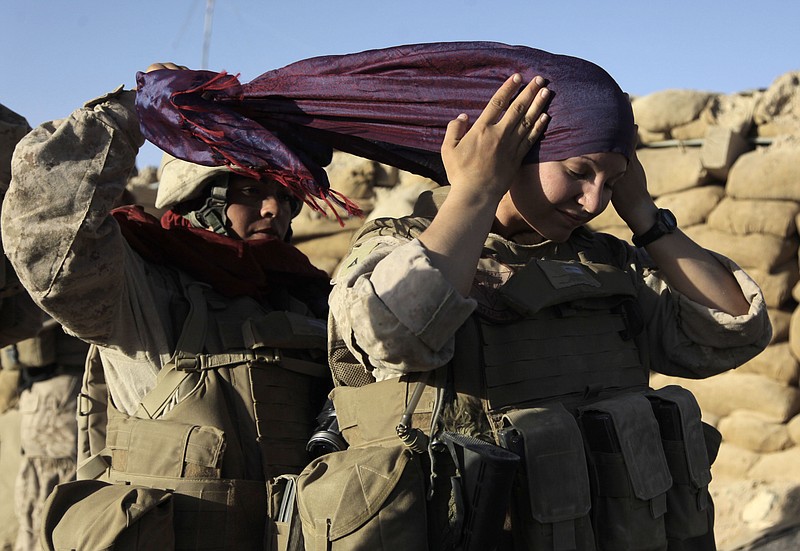 U.S. Marine Sgt. Monica Perez, of San Diego, left, helps Lance Cpl. Mary Shloss of Hammond, Ind. put on her head scarf in August 2009 before heading out on a patrol in the village of Khwaja Jamal in the Helmand Province of Afghanistan. Perez and Shloss were members of the Female Engagement Team whose mission was to engage with local Afghan women.