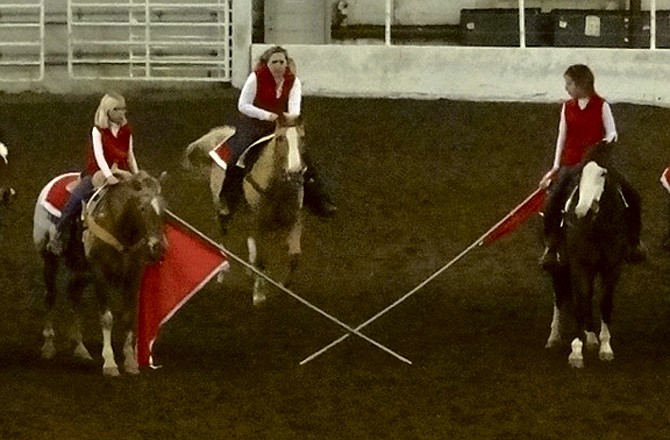 A rider prepares to jump her horse over crossed flags at the close of the Showme Thunder Drill Team's program.