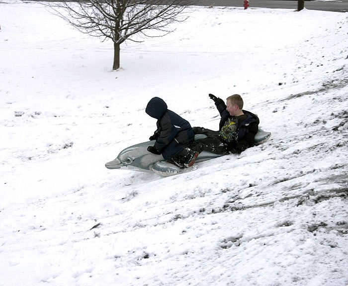 Dominic and Trenton enjoy a day off school, taking double advantage of the winter snow by riding a play dolphin down a snowy hill Monday afternoon. 