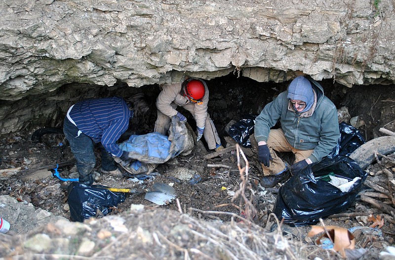 Volunteers dig out tires and trash at the entrance of the Goodwin Pit Cave. 