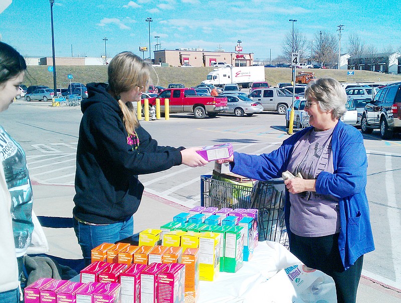 Pam Coots of Fulton buys a box of Girl Scout cookies from Troop 62503 in front of the Wal-Mart Supercenter in Fulton Saturday morning.