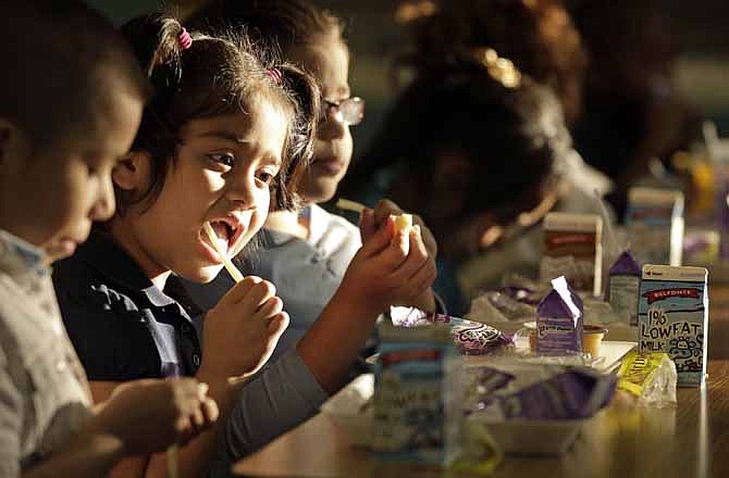 In this Jan. 23, 2012 photo, students at Garfield Elementary School eat dinner after classes as part of a new program in Kansas City, Mo. Too often it is after the fact that teachers discover their students are worrying less about math and reading and more about where the next meal comes from. So Doug White, principal of Garfield Elementary School in inner-city Kansas City, was relieved when his school, like many across the country, began offering dinner to students enrolled in after-school child-care or tutoring programs.