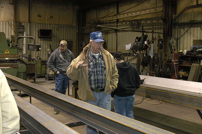 During an Adult Ag Education tour of Rackers manufacturing, owner Charles Rackers stands beside some metal which will become columns and explains how some of the metal is shaped, then either painted or galvanized.