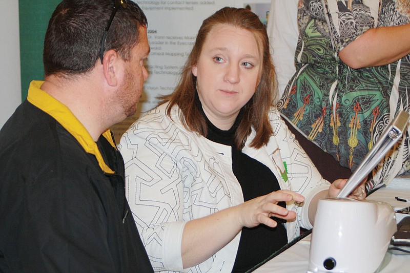 Michelle Sample, a representative of Vision Arts Eyecare Center in Fulton, demonstrates an electronic device that measures the level of antioxidents in eyecare patients to determine vulnerability to macular eye degeneration. Taking the free test Saturday was Mike McCray of Fulton. The booth was at the Callaway Business Exposition sponsored by the Kingdom of Callaway Chamber of Commerce.