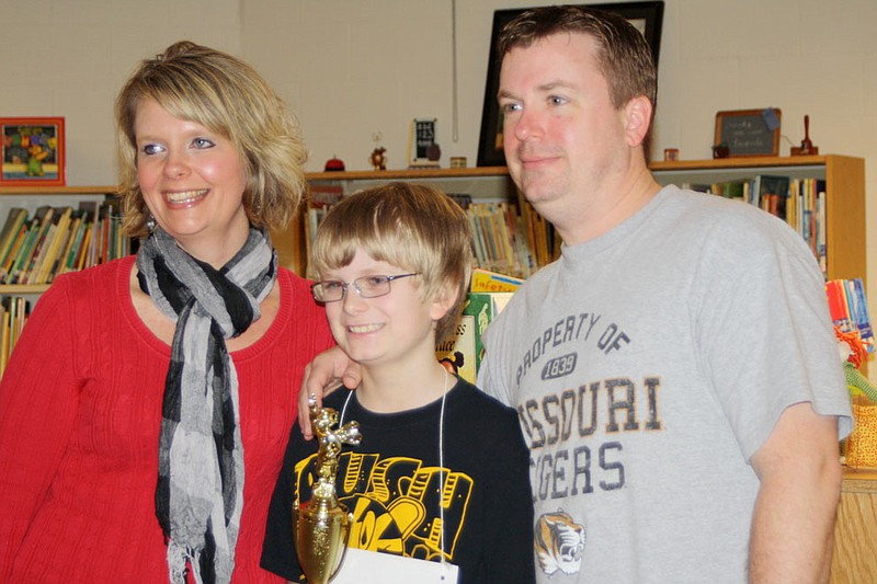 Brandon Rosenstengel, a fourth grader at Bush Elementary School, holds his trophy after winning first place in the Fulton Elementary School Spelling Bee Saturday at Bartley Elementary School. With him are his parents, Mandy and Jason Rosenstengel of Fulton.