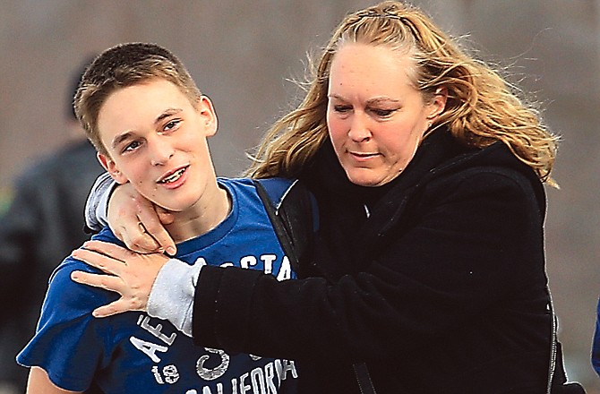 Doug Gasper, a ninth-grader at Chardon High School, is hugged by his mother, Sandy, as they leave Maple Elementary School in Chardon, Ohio. Students assembled at Maple Elementary School after a shooting took place at the high school.