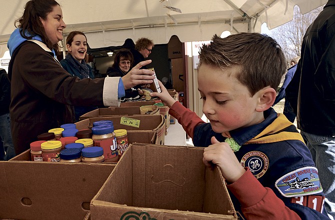 August Grantham of Cub Scouts Pack 316 unpacks a box of food while volunteers sort out the donations at the Jefferson City Samaritan Center during the Boy Scouts' annual "Scouting For Food" drive on Saturday. 