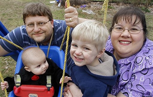 In this photo taken Feb. 10, 2012, Nathen and Melissa Cobb pose for a photo with their two children Joshua, 3, and Savannah, 7 months, at their home in Riverton, Ill. The Cobbs tried to refinance their home last year and didn't qualify for the loan because of medical bills that had been sent to a collection agency. They were surprised because the bills had been paid. They now know that the collection action can stay on their credit report for seven years.