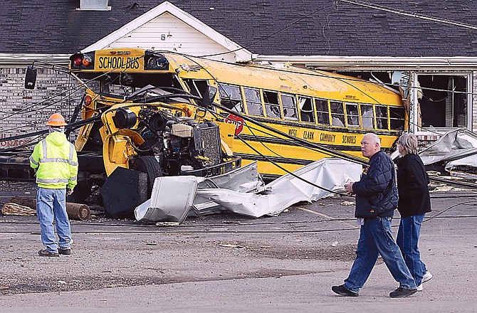 Residents walk past a school bus thrown into this restaurant by tornado in Henryville, Ind., on Sunday. Calm weather gave dazed residents of storm-wracked towns a respite on Sunday as they dug out from a chain of tornadoes that cut a swath of destruction from the Midwest to the Gulf of Mexico.
