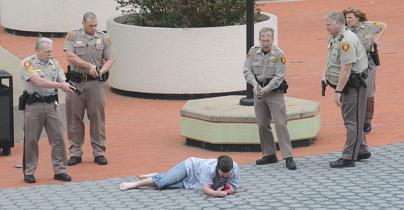 In this photo provided by John Fancher, sheriff's deputies surround a man who was wounded in an exchange of gunfire Wednesday with law enforcement officers on the plaza between the library and the Tulsa County Courthouse in Tulsa, Okla. The shooter, 
a sheriff's deputy, and a bystander were wounded during the exchange, police said. 