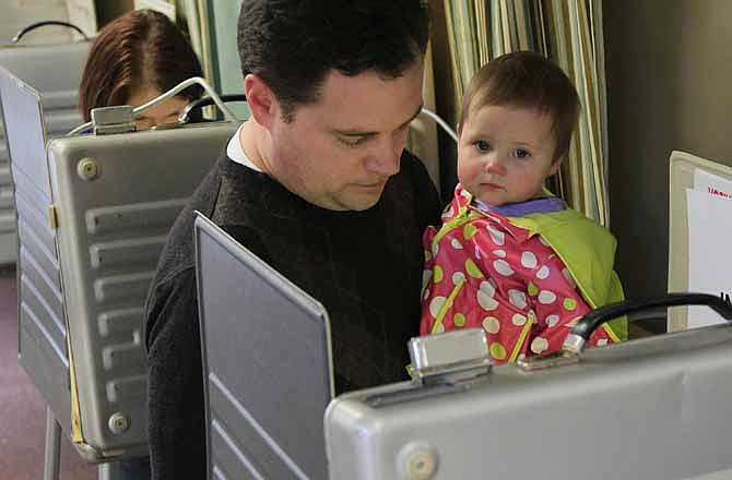Marc Lewis holds daughter Alexa, nine-months-old, as he votes at the Heritage Universalist Unitarian Church,Tuesday, March 6, 2012, in Cincinnati.