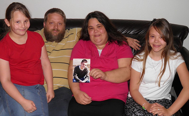 The Miller family (Kylie, Jason, Jennifer and Ashley) pose with a picture of Joshua, who died after a car accident. When Jason filed the family's taxes, he discovered his son's identity had been stolen after he died.