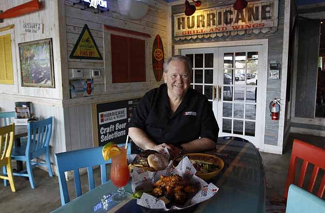In this photo taken Tuesday, March 20, 2012, Martin O'Dowd poses for a portrait at the Hurricane Grill and Wings in Lake Worth, Fla. Some diners at the restaurant had been limiting themselves to a small order of the chain's saucy chicken wings and a glass of tap water. These days, many of those folks are upgrading to a bigger order of as many as 15 wings and a soda. 