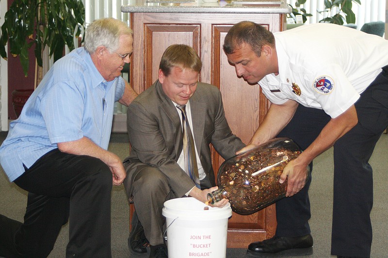 The Rev. Ron Baker, left, retired pastor of the Southside Baptist Church in Fulton, Tuesday donated several years of accumulated pennies to a fund to finance a museum at the Missouri Fireman's Memorial at Kingdom City. With him are Rodney Bax, center, of Bank Star One where the pennies were counted and Fulton Asssistant Fire Chief Kevin Coffelt.