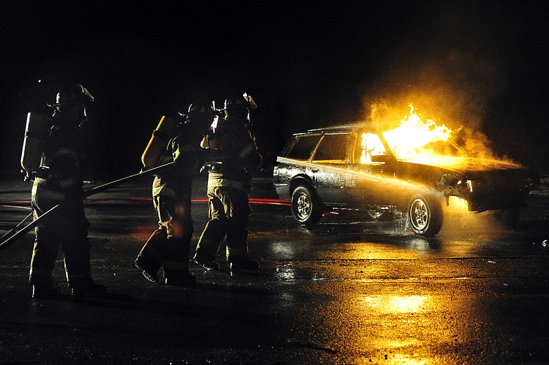 Three Firefighters cautiously approach a burning car Monday during Cole County Fire Protection District's annual training exercise at the Cole County Maintenance Facility on Montecello Road. Approxamietly 30 firefighers practiced putting out different fuel fire scenarios during the training.