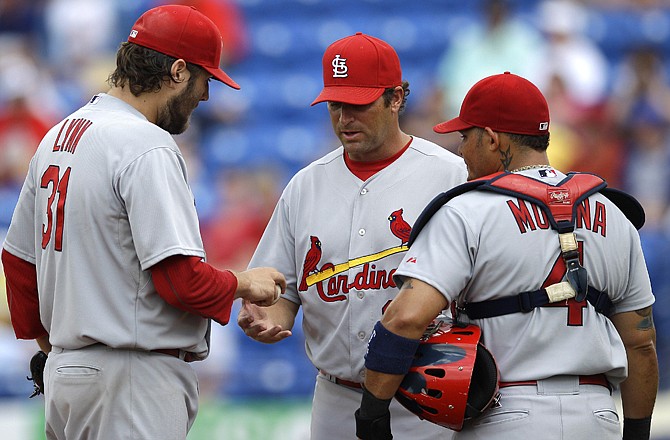 New Cardinals manager Mike Matheny (center) relieves pitcher Lance Lynn (left) during a spring training game this year. Matheny is one of several new faces to the Cardinals-Brewers rivalry this season. Catcher Yadier Molina is with Lynn and Matheny.