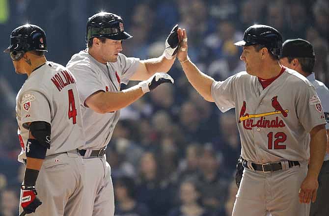 St. Louis Cardinals' David Freese, center, receives a high-five from teammate Lance Berkman (12) after hitting a two-run home run in the third inning of an opening day game against the Milwaukee Brewers, Friday, April 6, 2012, in Milwaukee. Cardinals' Yadier Molina (4) looks on.