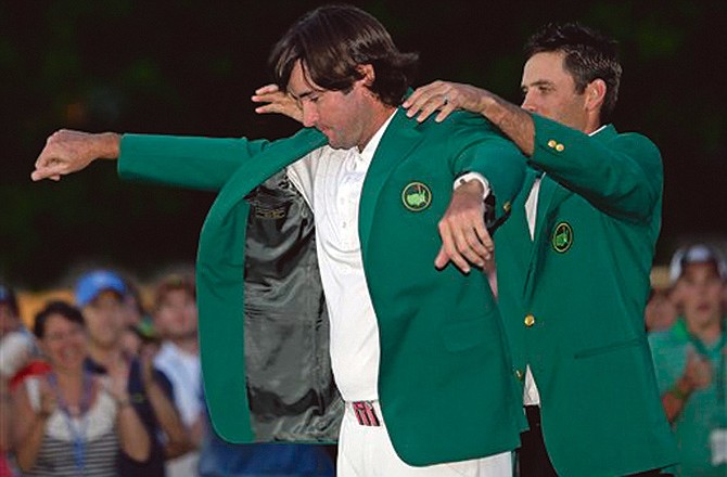 Charl Schwartzel, right, helps Bubba Watson put on the green jacket after winning the Masters golf tournament following a sudden death playoff on the 10th hole.
