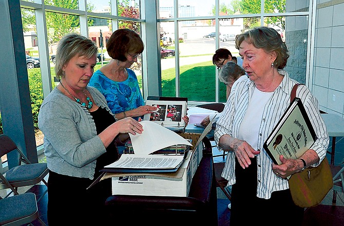 Karen Enloe, left, and Laramie Thompson look over the items Myrene Duncan, right, brought in Monday evening at the Miller Performing Arts Center atrium. Duncan graduated from Jefferson City High School in 1949, and was sharing stories and photos from her time at school. The district is collecting items for a yearbook to celebrate its 175th anniversary in 2013.
