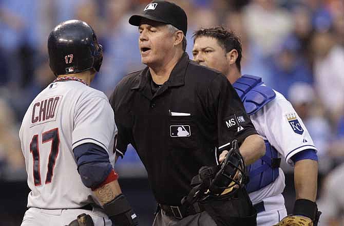 An umpire, center, keeps Cleveland Indians' Shin-Soo Choo (17) and Kansas City Royals catcher Humberto Quintero apart after Choo was hit by a pitch thrown by Jonathan Sanchez during the third inning of a baseball game on Saturday, April 14, 2012, in Kansas City, Mo.