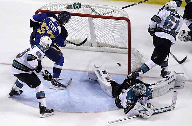 St. Louis Blues' David Perron (57) scores past San Jose Sharks goalie Antti Niemi, of Finland, Andrew Desjardins (69) and Justin Braun (61) during the third period in Game 2 of an NHL Stanley Cup first-round hockey playoff series Saturday, April 14, 2012, in St. Louis. The Blues won 3-0. 