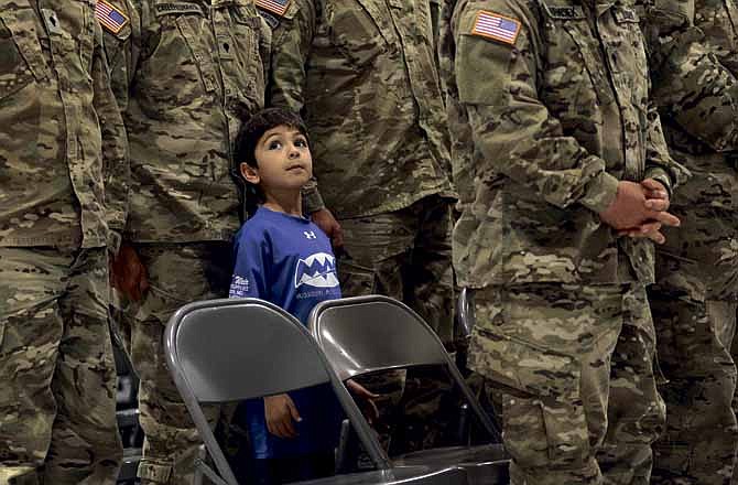 Santiago Calle stands in formation with his dad, Spc. Juan Calle, during the invocation and opening remarks as the Missouri National Guard 548th Transportation Company celebrated their homecoming at the Ike Skelton Training Site in Jefferson City on Saturday following a year-long tour in Afghanistan. 