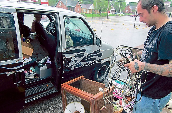 Tony Hance looks over some cables and cords that he found by a curb on Clark Avenue on Sunday afternoon before placing it in his vehicle. Hance picks up items in the city's annual spring cleanup, then sells them to scrapyards.