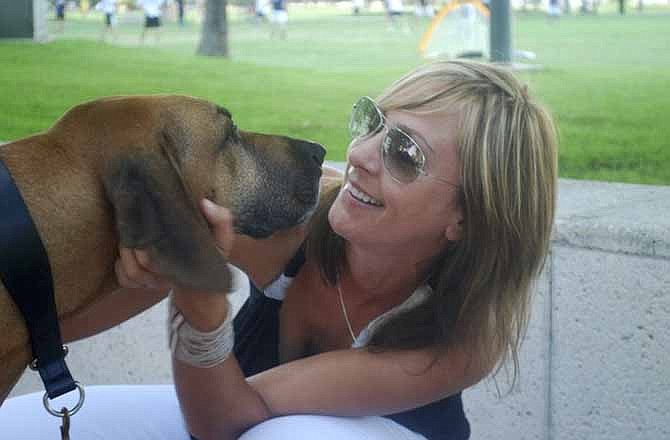 In this 2011 photo released by Sniff Pet Candles, Jenn Mohr, founder of Sniff Pet Candles, pets Rufus her 8-year-old Rhodesian ridgeback rescue dog in Miami, Fla. Mohr says she can't forgive Republican presidential hopeful Mitt Romney for making his dog ride on top of the car during a 1983 family trip to Canada. But many dog owners feel the whole doggone issue is a distraction.