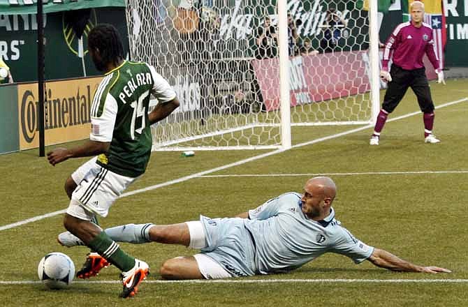 Sporting Kansas City defender Aurelian Collin, front right, slides in for the ball against Portland Timbers forward Jorge Perlaza, left, during the first half of their MLS soccer game in Portland, Ore., Saturday, April 21, 2012. Sporting KC goalie Jimmy Nelson, back right, watches the play. 