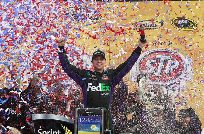 Denny Hamlin celebrates in Victory Lane after winning the NASCAR Sprint Cup Series auto race at Kansas Speedway on Sunday in Kansas City, Kan.