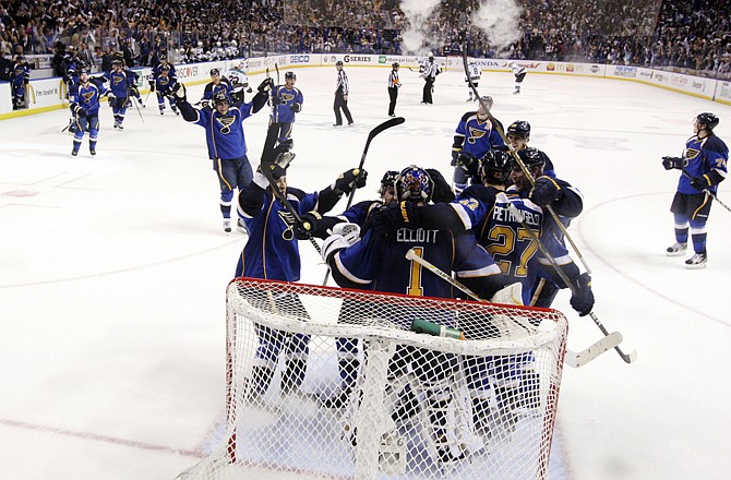 St. Louis Blues players celebrate with goaltender Brian Elliott as time expires against the San Jose Sharks in Game 5 of the first-round playoff series Saturday in St. Louis.