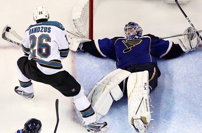 Blues goaltender Brian Elliott sprawls out to defend against Michael Handzus of the Sharks during Saturday night's game in St. Louis.