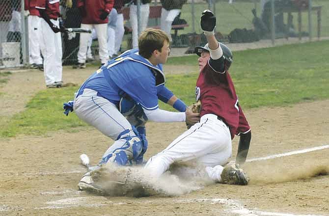 Fatima catcher Nolan Bax tags out Jake Mebruer of Linn to complete a double play in the bottom of the second inning Friday in Linn.