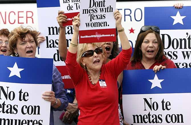 In this March 6, 2012 file photo Mary Green, Peg Armstrong and Jan Perrault hold up signs during Women's Health Express, a bus event held in San Antonio, Texas, to protest the attempt to cut Planned Parenthood out of the state's Women's Health Plan.