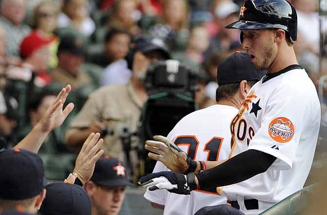 Houston Astros' Jordan Schafer, right, is greeted in the dugout after scoring from third base on a single by Carlos Lee against the St. Louis Cardinals in the first inning of a baseball game, Friday, May 4, 2012, in Houston.