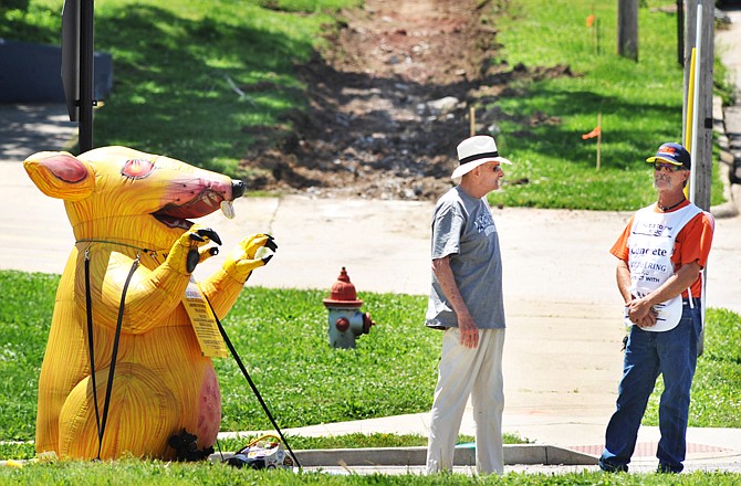 Tim Thurman of Laborers Local 662, at right, visits with pedestrian Terry Larkin as he keeps company with an inflatable rat to protest the city's contract with a non-union company hired to construct replacement sidewalks on Broadway Street.