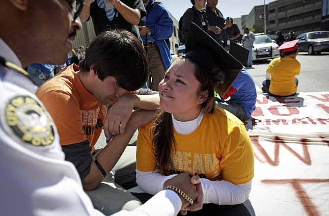 In this Tuesday, April 5, 2011 photo, illegal immigrant Virdiana Martinez, right, is comforted by activist Mohammad Abdollahi, as Major K. E. Williams, left, of the Atlanta Police Department warns her of arrest unless she moves while protesting for rights for higher education for illegal immigrants in Atlanta. When Williams informed her she could get up now and that she's made her point, Martinez asked him if his ancestors had that opportunity.